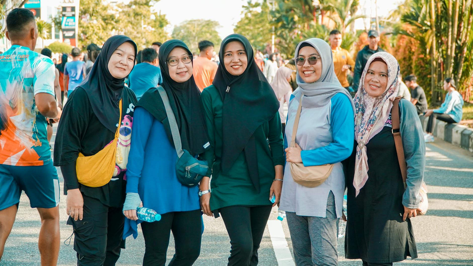 A group of women in hijabs smiling outdoors at a public event, showcasing cultural diversity and unity.
