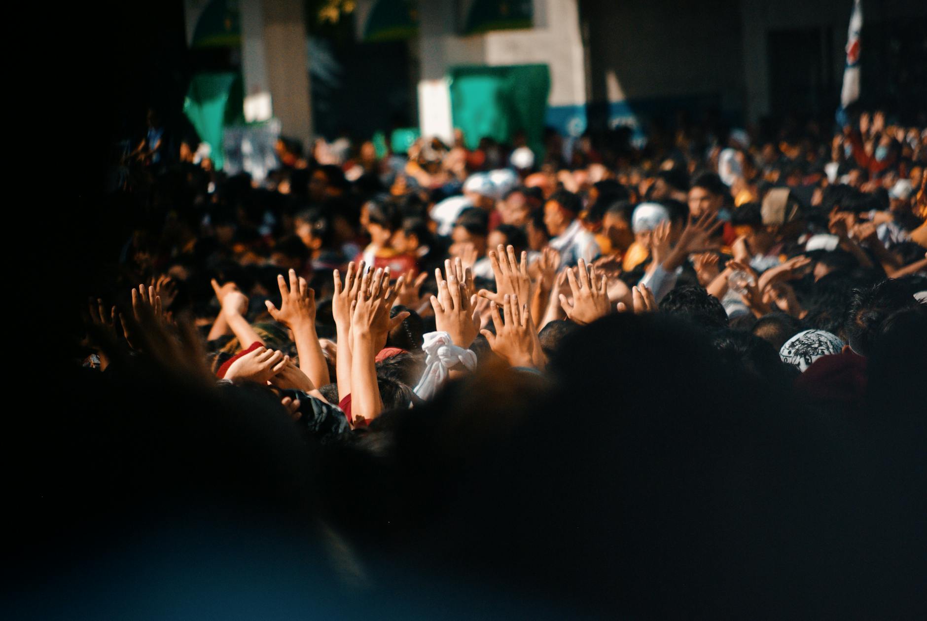 A lively crowd of people with hands raised collectively in an outdoor celebration.