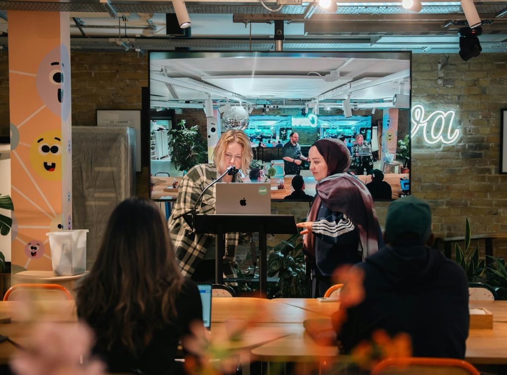 Informal presentation in a modern office setting with two women collaborating at a laptop.