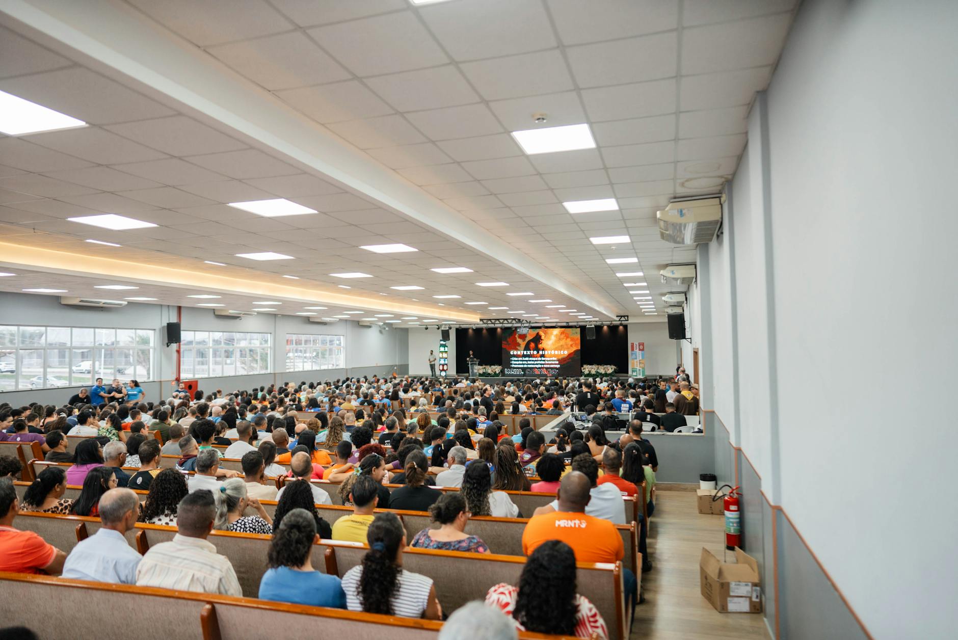 Large audience gathered in a spacious auditorium for a presentation or event with stage view.