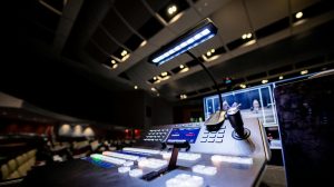 Contemporary music console with buttons and glowing lamp under ceiling with lights in dark studio