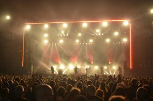 Dynamic live concert with band on stage, lighting effects, and enthusiastic crowd at night.