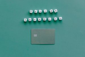 Flat lay of credit card and 'Online Shopping' text on green background, symbolizing ecommerce.