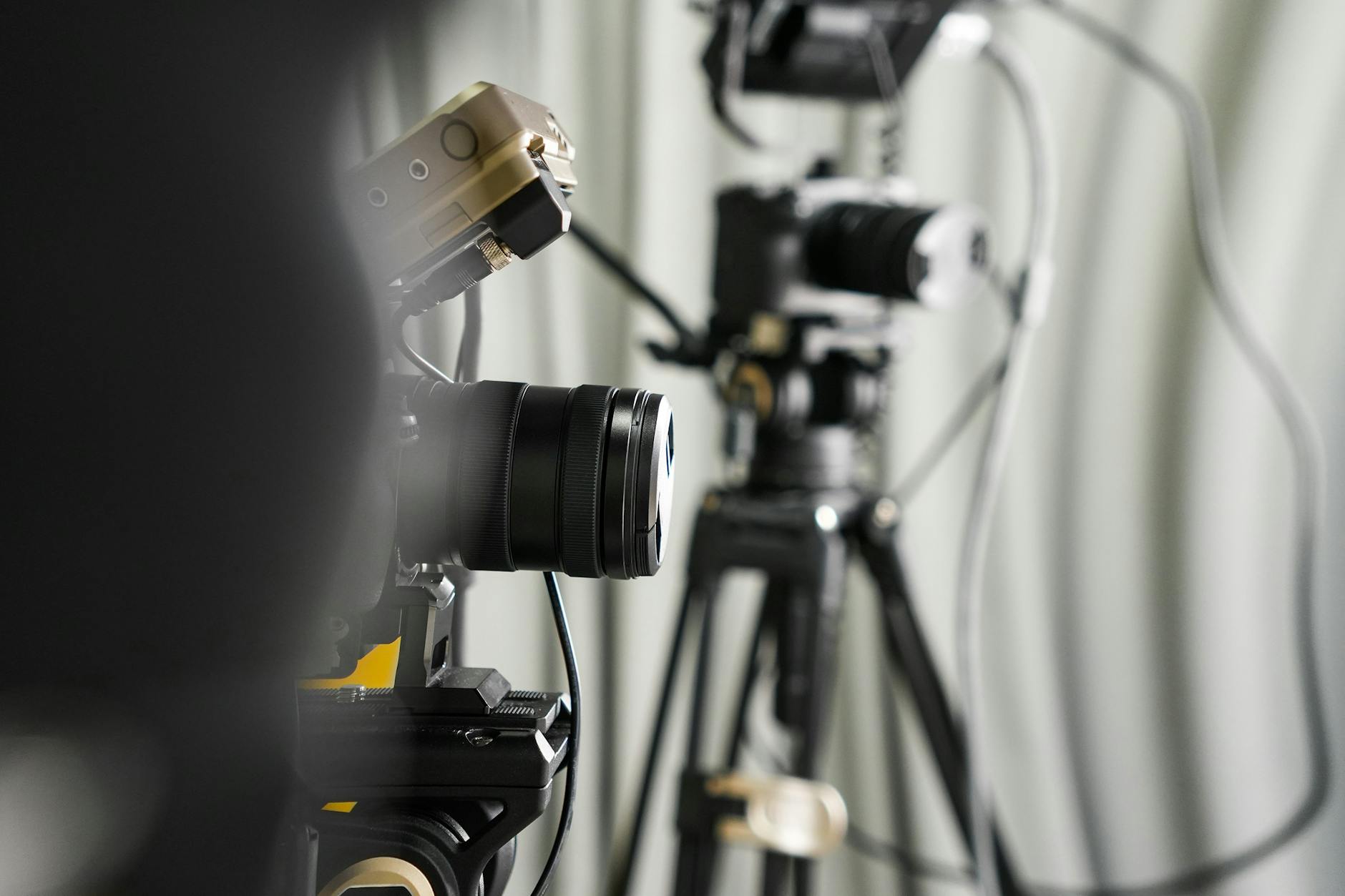 Close-up of professional video cameras on tripods in a studio setting.