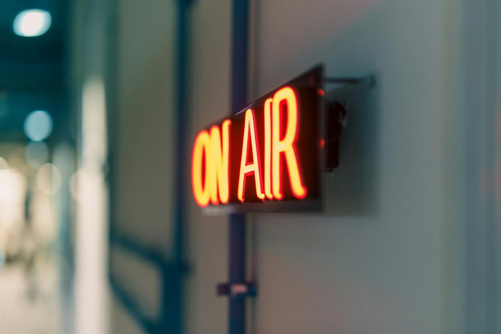 Bright red 'On Air' neon sign captured indoors, ideal for media content.