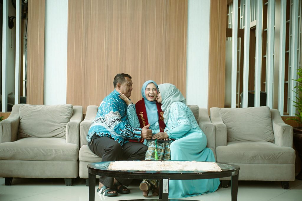 Happy family celebrating a graduation achievement, sitting on a sofa in a cozy indoor setting.
