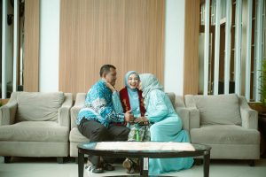 Happy family celebrating a graduation achievement, sitting on a sofa in a cozy indoor setting.