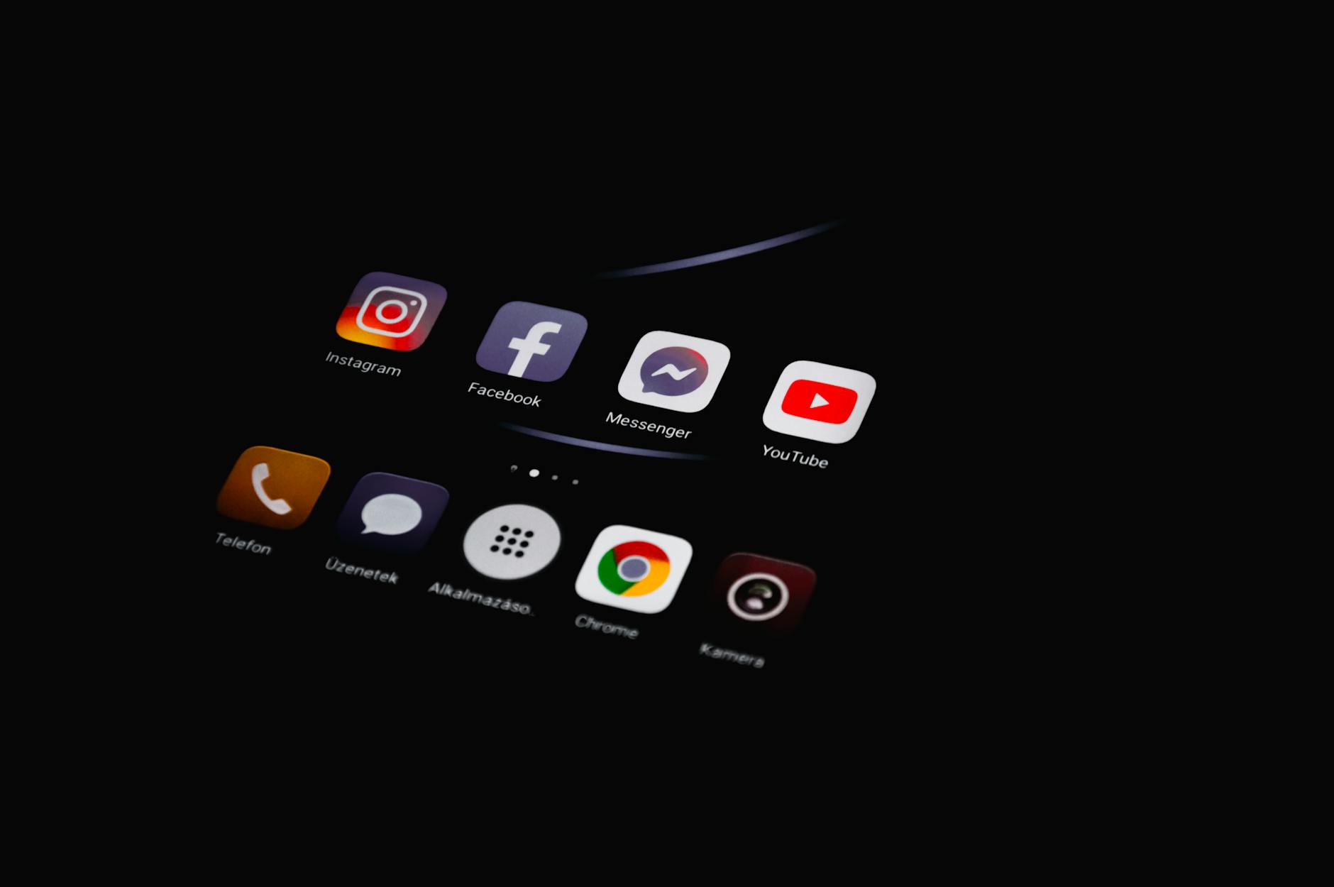 Close-up of smartphone displaying popular social media apps in dim lighting.