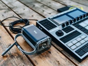 A contemporary DJ console and portable speaker placed on a wooden surface, ideal for music production enthusiasts.