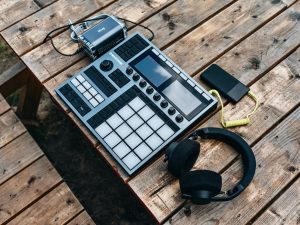 Top view of music production equipment including a controller and headphones on a wooden table.