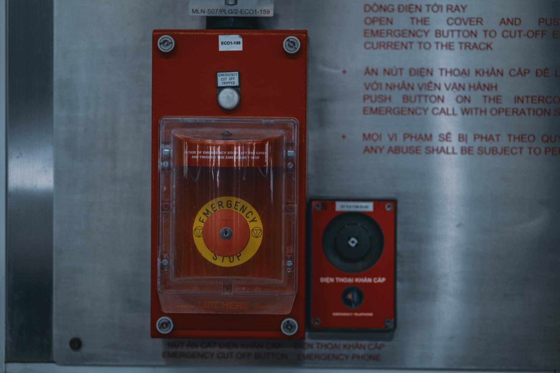 Close-up of an emergency stop button with warning text on an industrial panel.