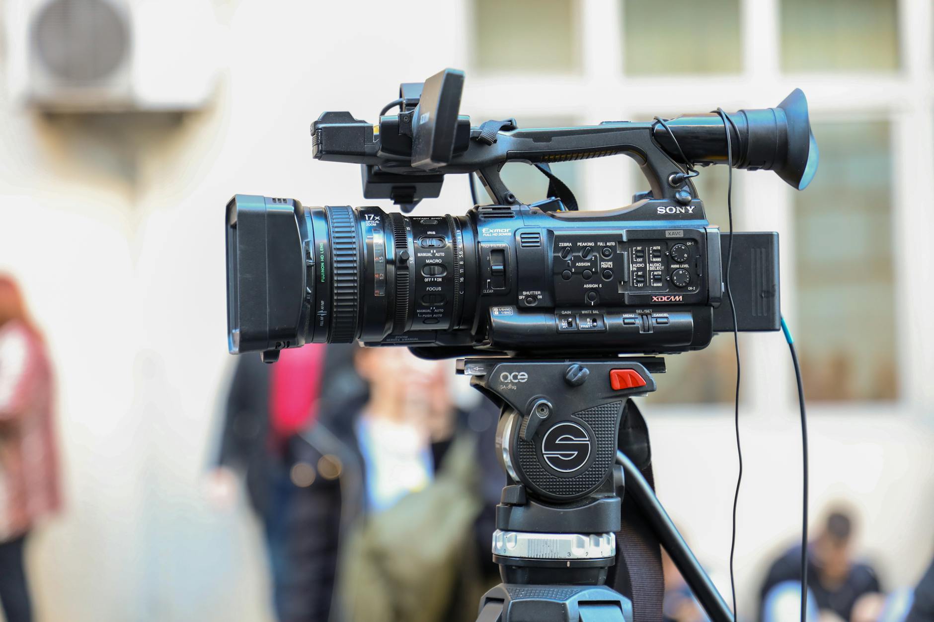 Close-up of a Sony video camera mounted on a tripod for outdoor filming.