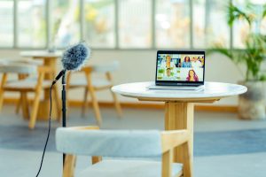 A cozy podcast setup with a laptop and microphone in a modern interior setting.