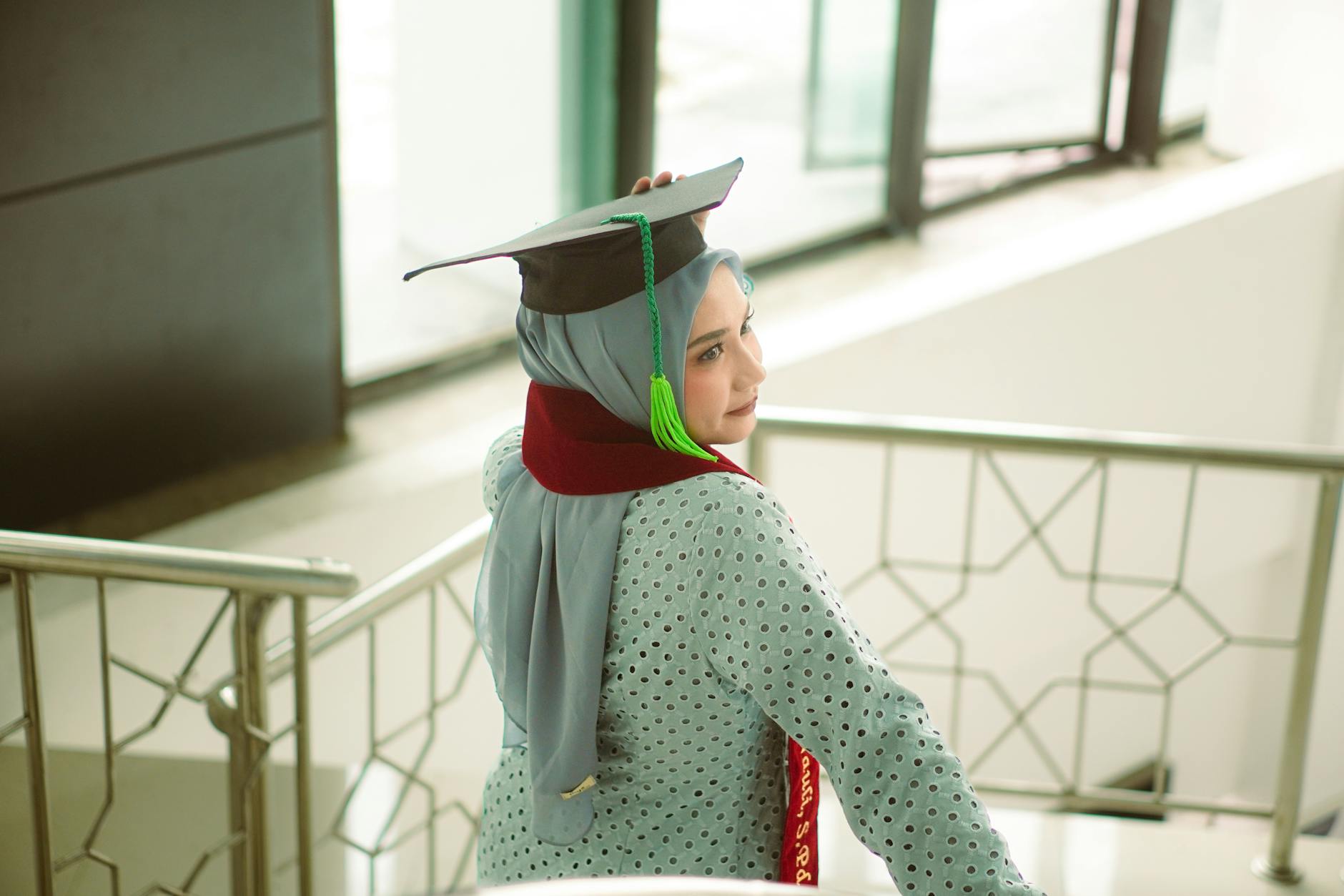 A young woman in a hijab wears a graduation cap, symbolizing success and achievement.