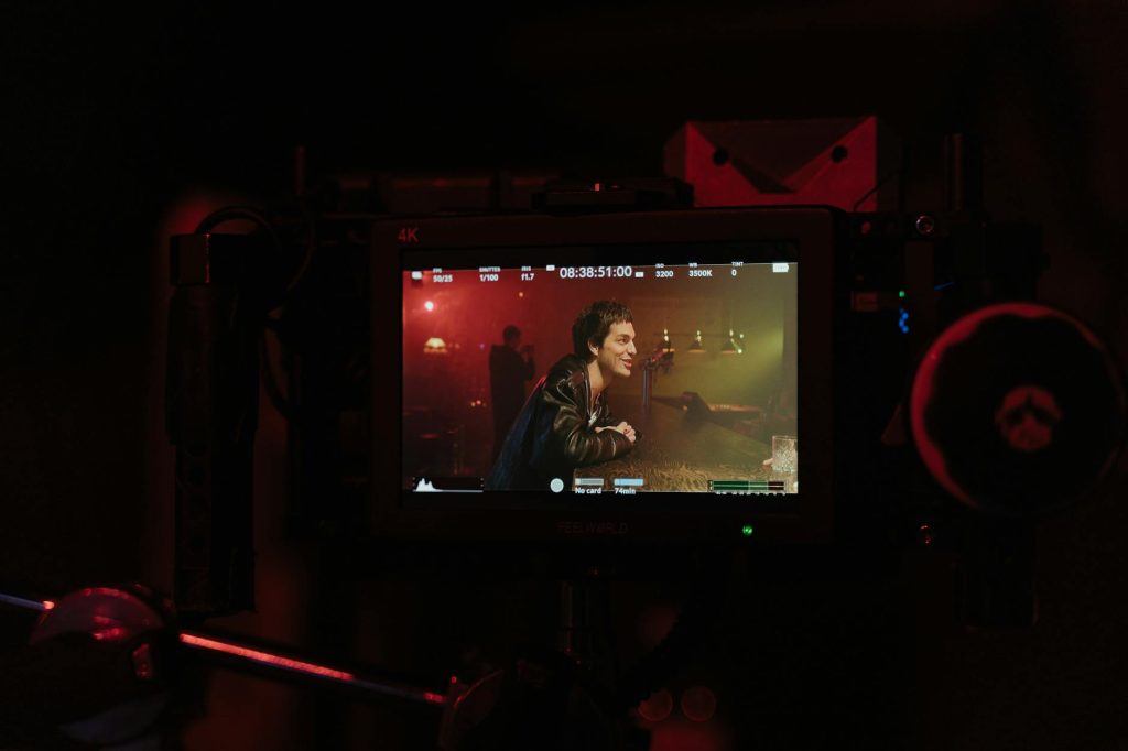 Close-up of a video monitor showing a filming scene in a dimly lit bar setting.