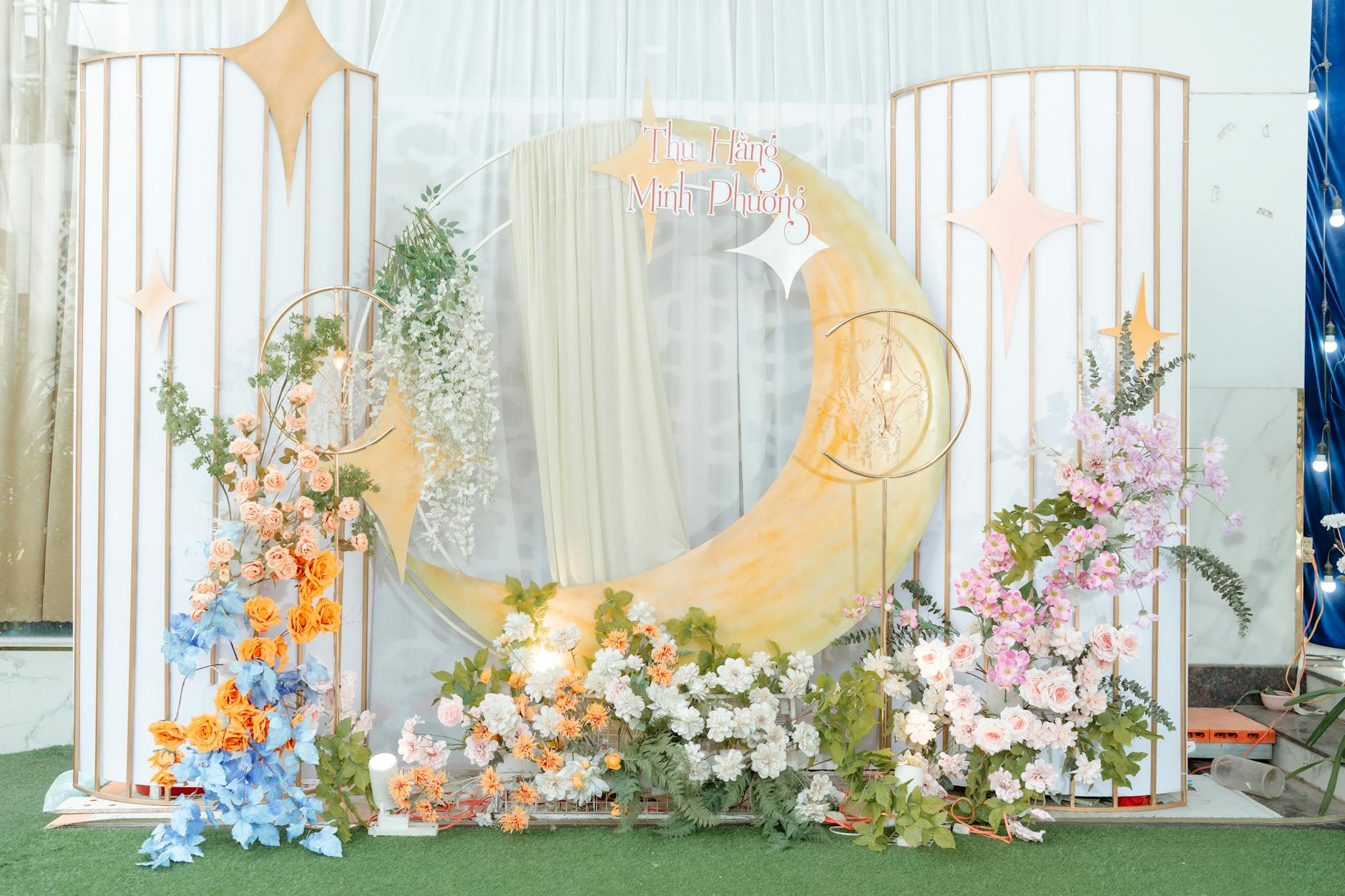Charming floral moon-themed backdrop for an event with pastel colors and celestial decorations.