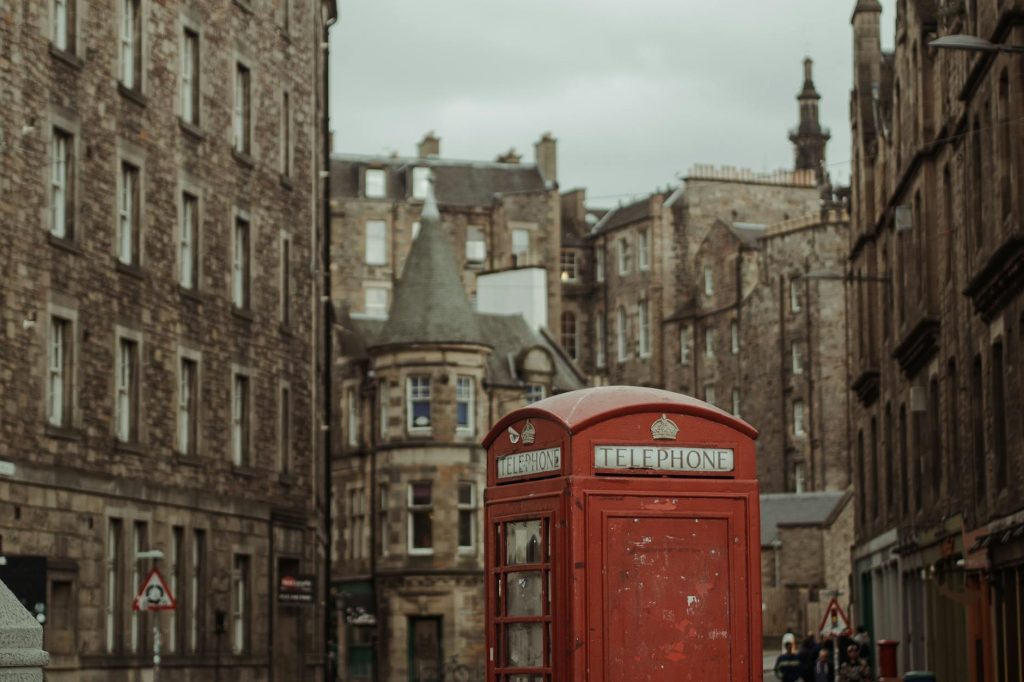 Classic red telephone booth in historic Edinburgh street, Scotland.
