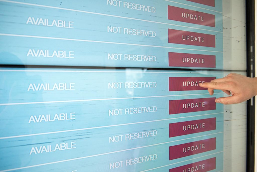 A hand interacts with a digital touchscreen interface showing availability and update options.