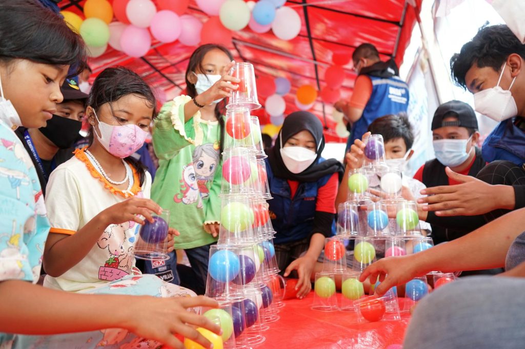 Kids having fun stacking colorful balls during a group activity at an indoor event.