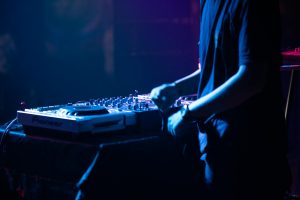 DJ in action adjusting controls on a DJ console during a live performance at a club.