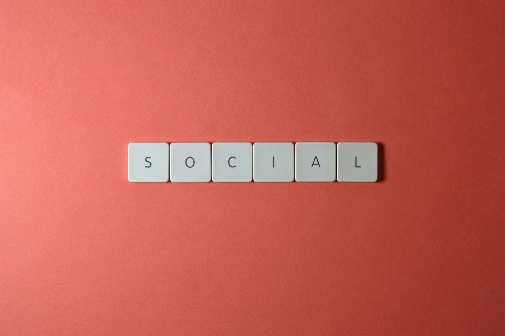 Close-up of the word 'SOCIAL' formed with tiles on a red surface, offering copyspace.