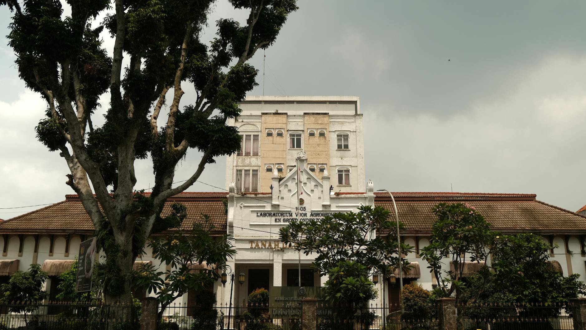 Outdoor view of a historic laboratory building surrounded by lush trees, under a cloudy sky.