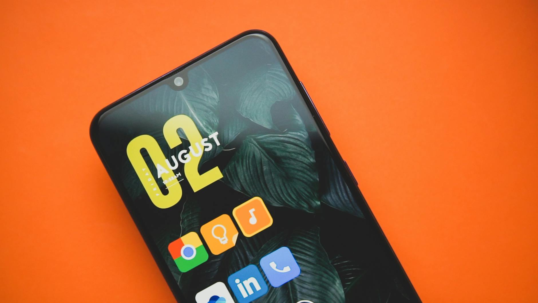 Close-up of a smartphone with colorful app icons on an orange background.