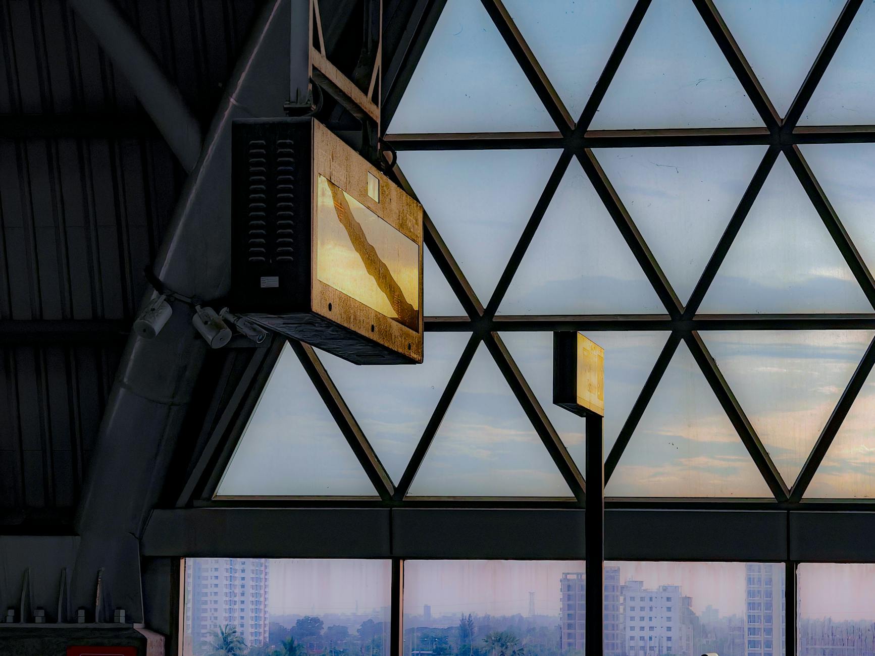 Geometric glass architecture inside a modern building at sunset with a city skyline.