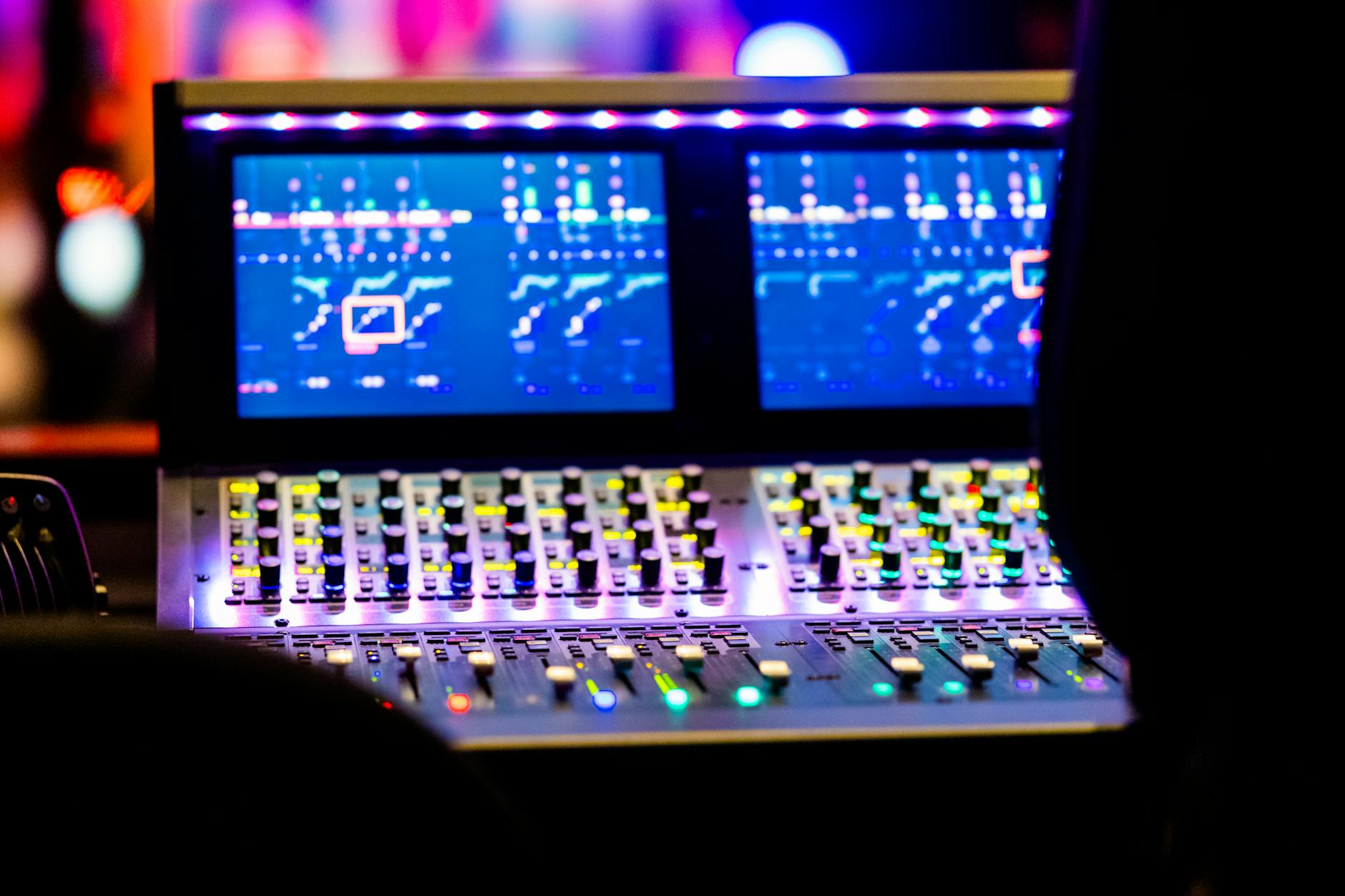 Close-up view of a professional sound mixing console with lit-up controls in a music studio.