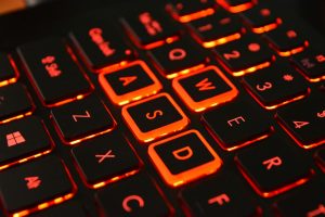 Detailed shot of an illuminated gaming keyboard with red backlight focusing on WASD keys.