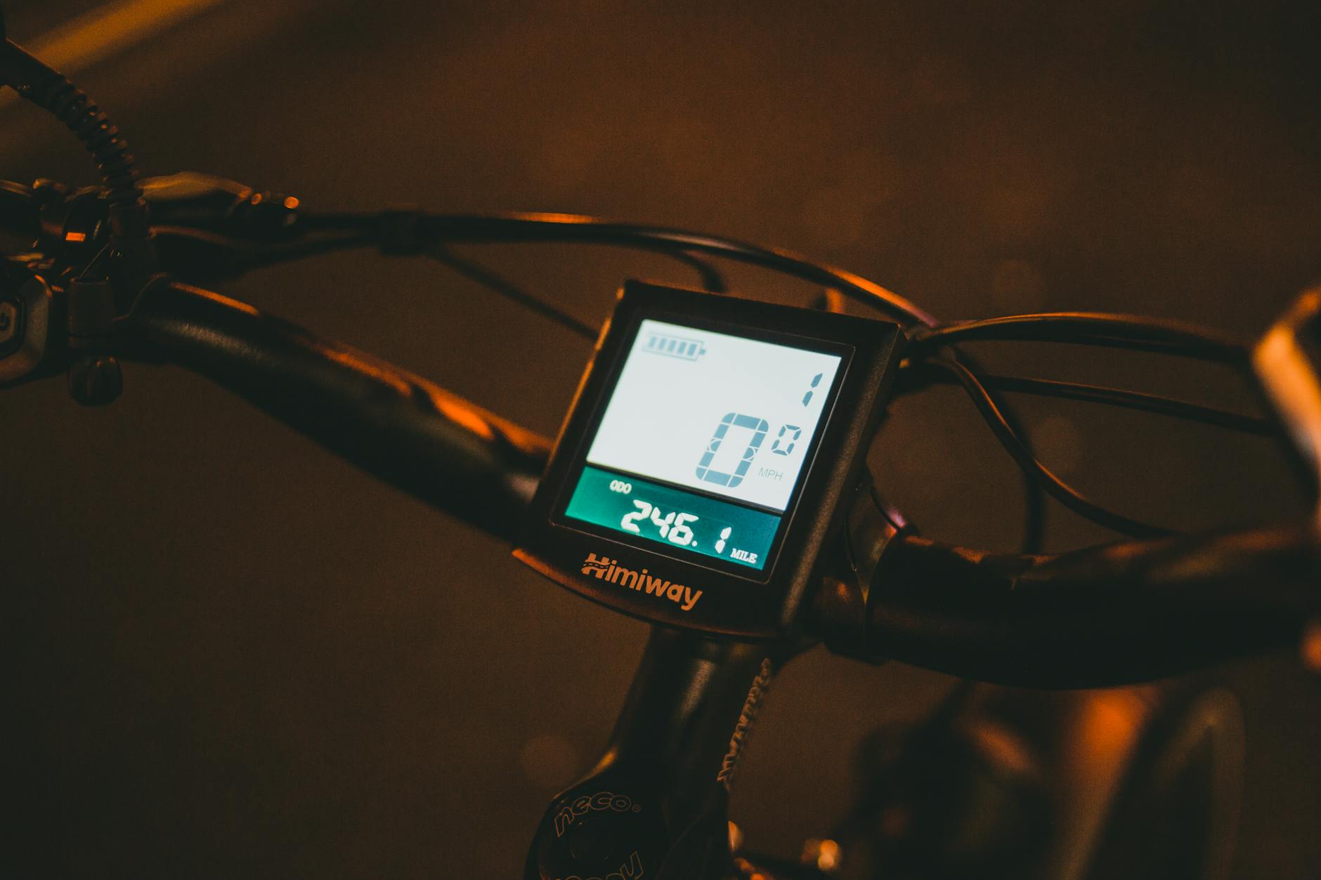 Close-up of an electric bike's digital display showing speed and battery life during nighttime cycling.