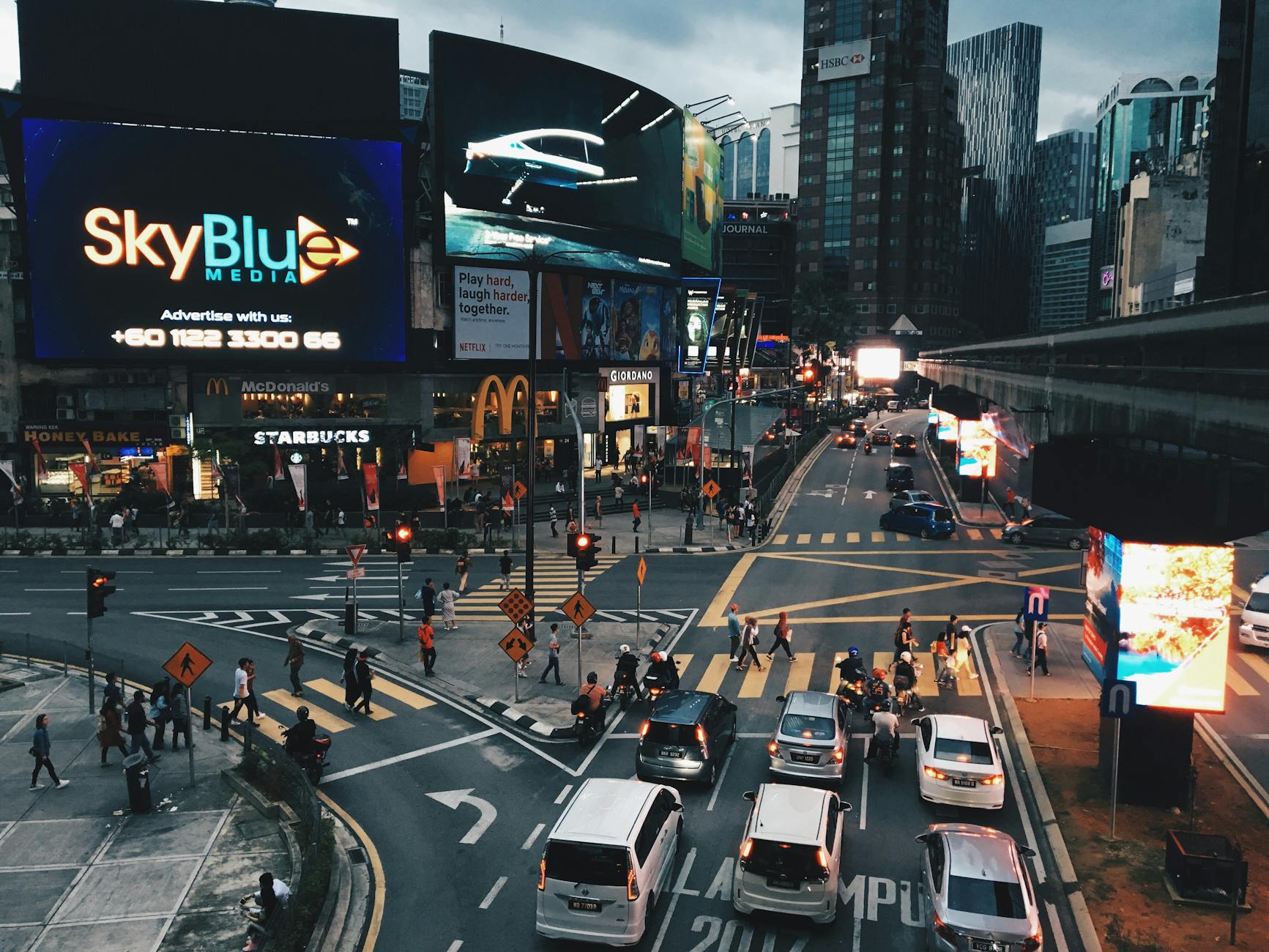 Evening cityscape in Kuala Lumpur with vibrant billboards and bustling traffic.