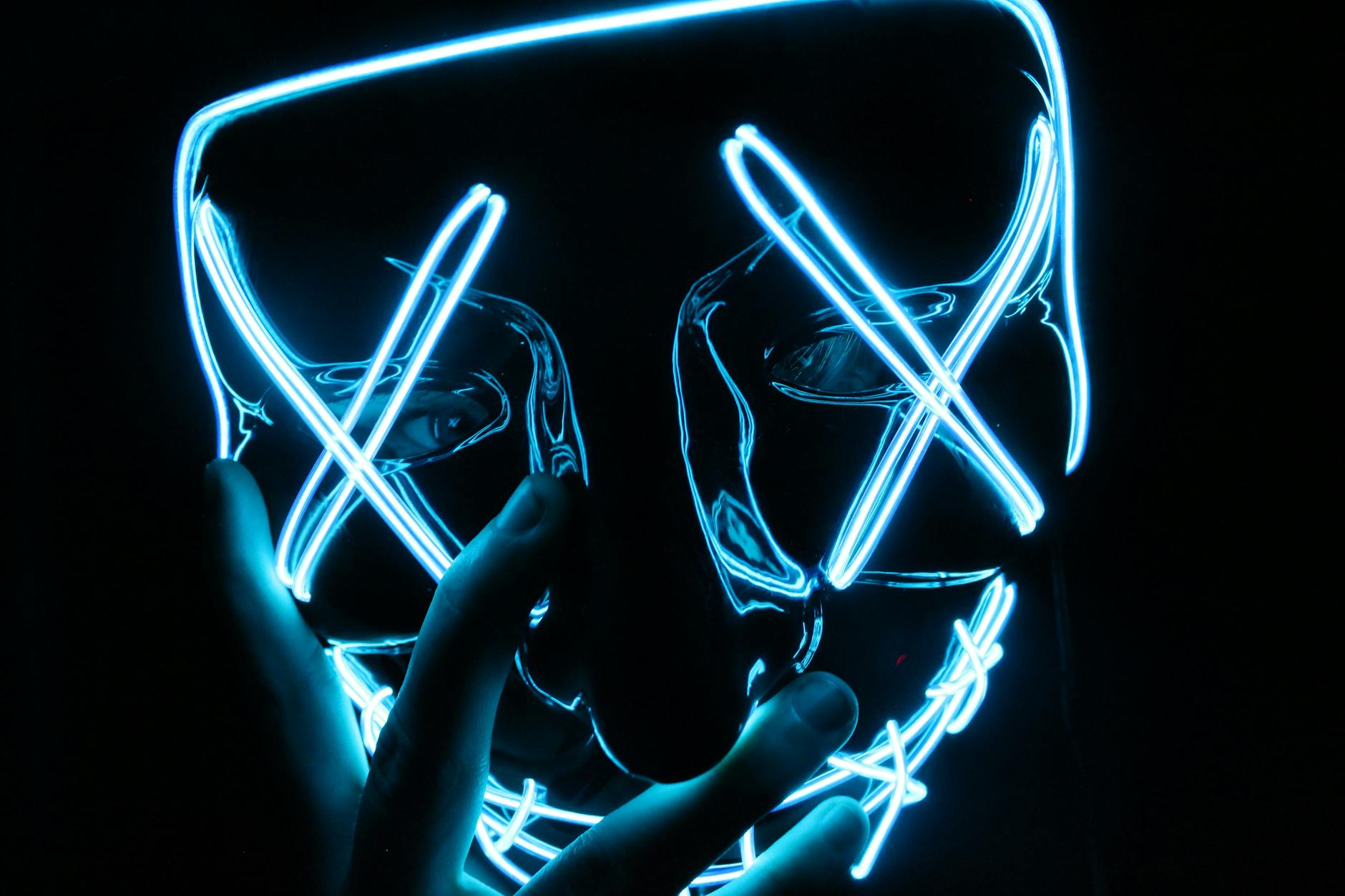 Vibrant neon LED mask with glowing shapes on a dark background.