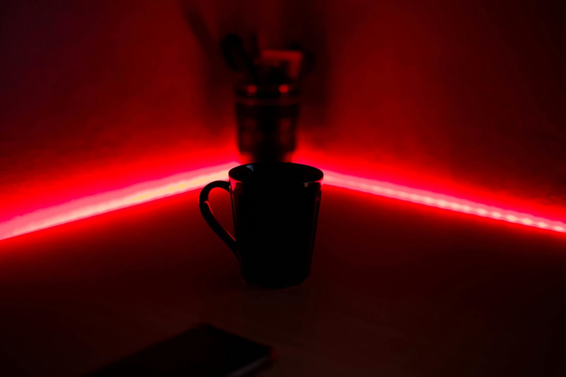A black cup illuminated by red LED lights in a dark indoor setting, offering a moody atmosphere.