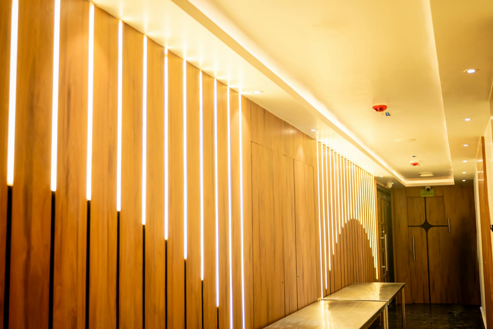 Elegant hallway with modern wood paneling and ambient lighting in a hotel setting.