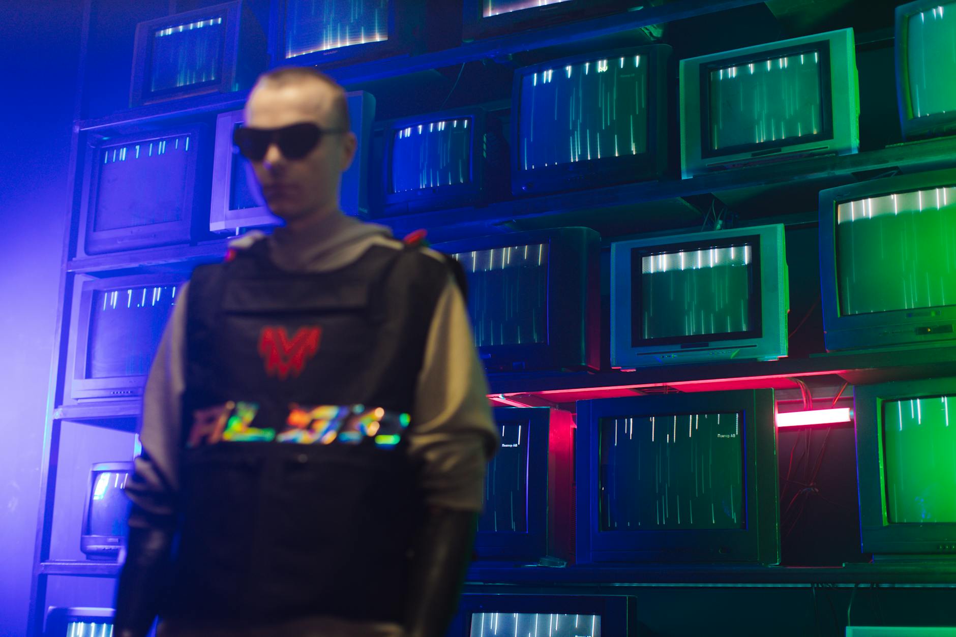 Futuristic cyberpunk setting with a man in sunglasses and vintage TVs displaying static lights.
