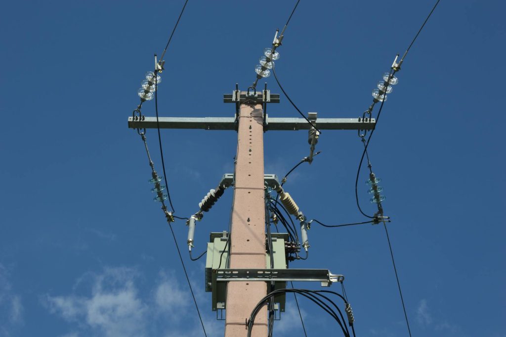 Low angle view of a utility pole with power lines against a blue sky.