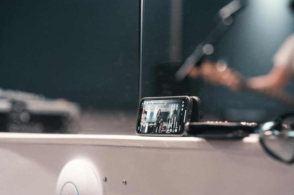 A smartphone recording a live band performance at an indoor event.
