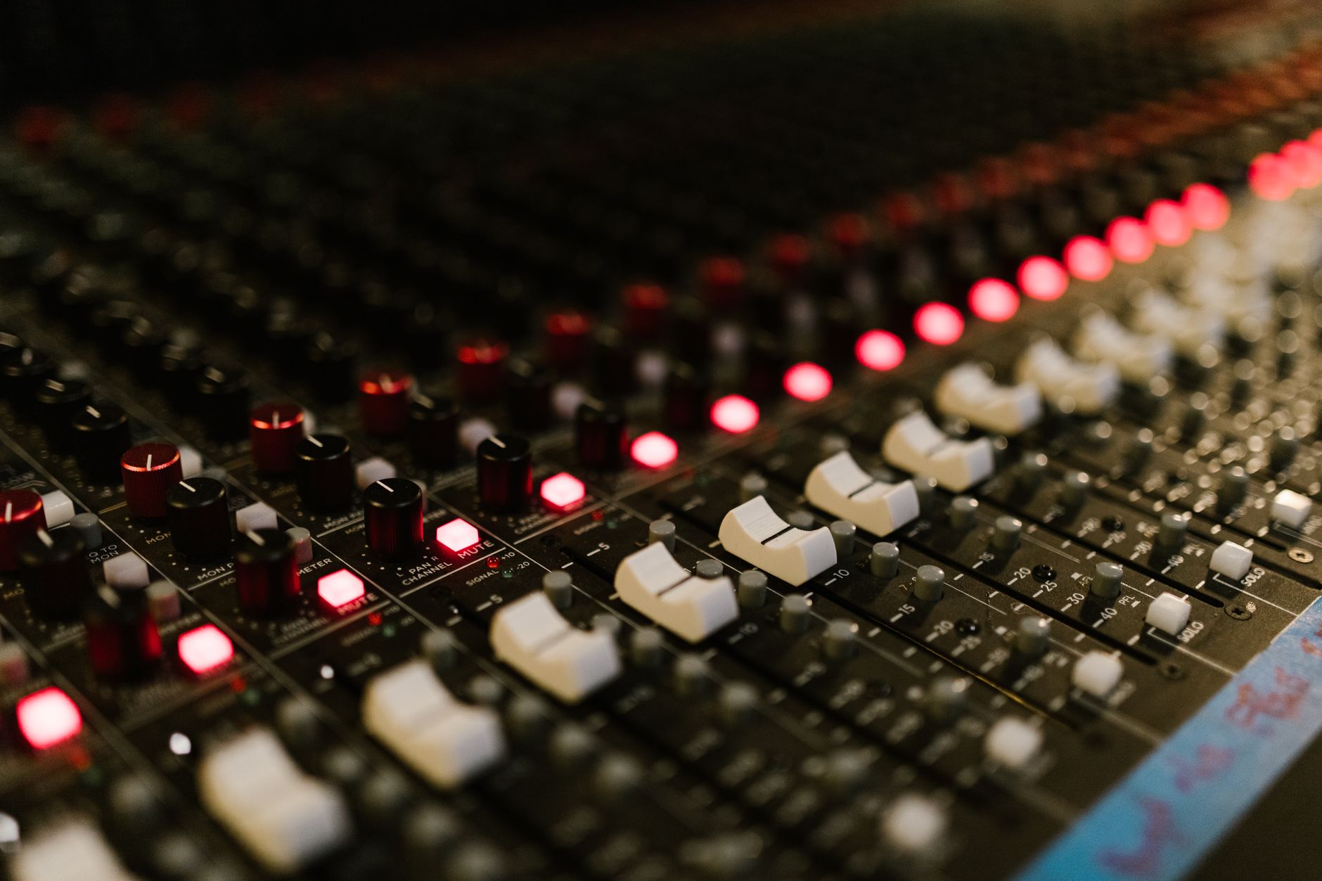 Close-up of a sound mixing console with illuminated control knobs in a music studio.