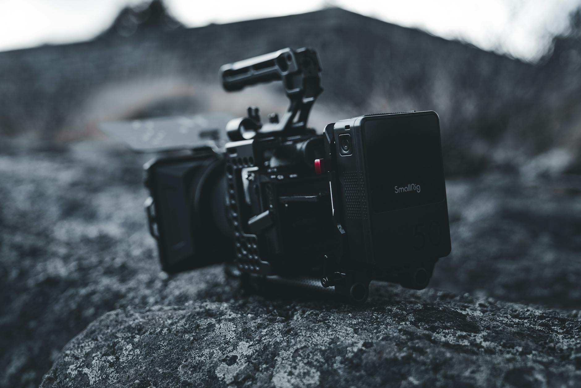 Close-up of a professional video camera rig on rocky outdoor terrain, showcasing high-end filming gear.