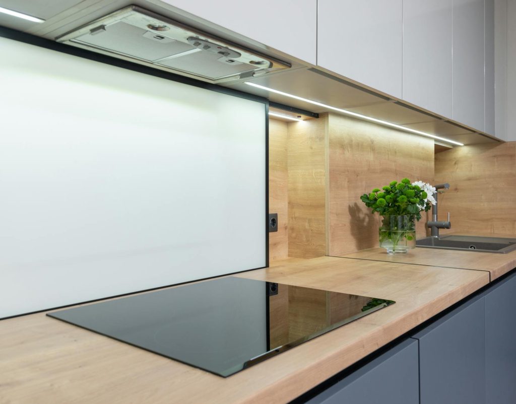 Built in cook top under hood and cupboard in contemporary kitchen with flowers in vase