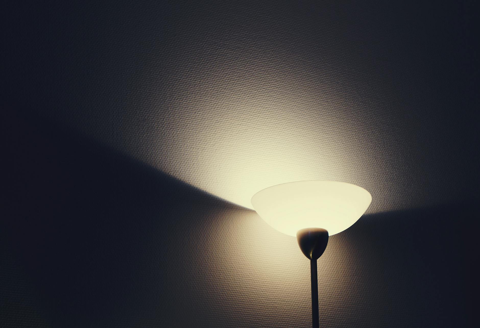 A warmly glowing wall lamp casting soft shadows on a textured wall, creating a cozy ambiance.