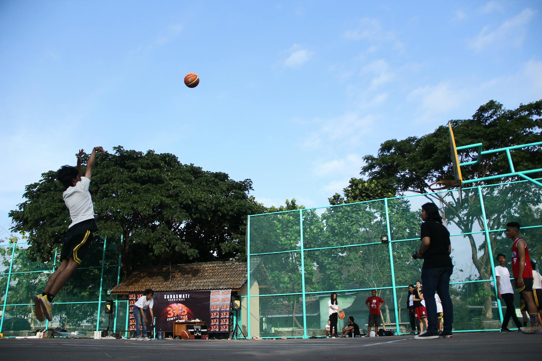 Players enjoying a lively game of basketball on a sunny outdoor court.