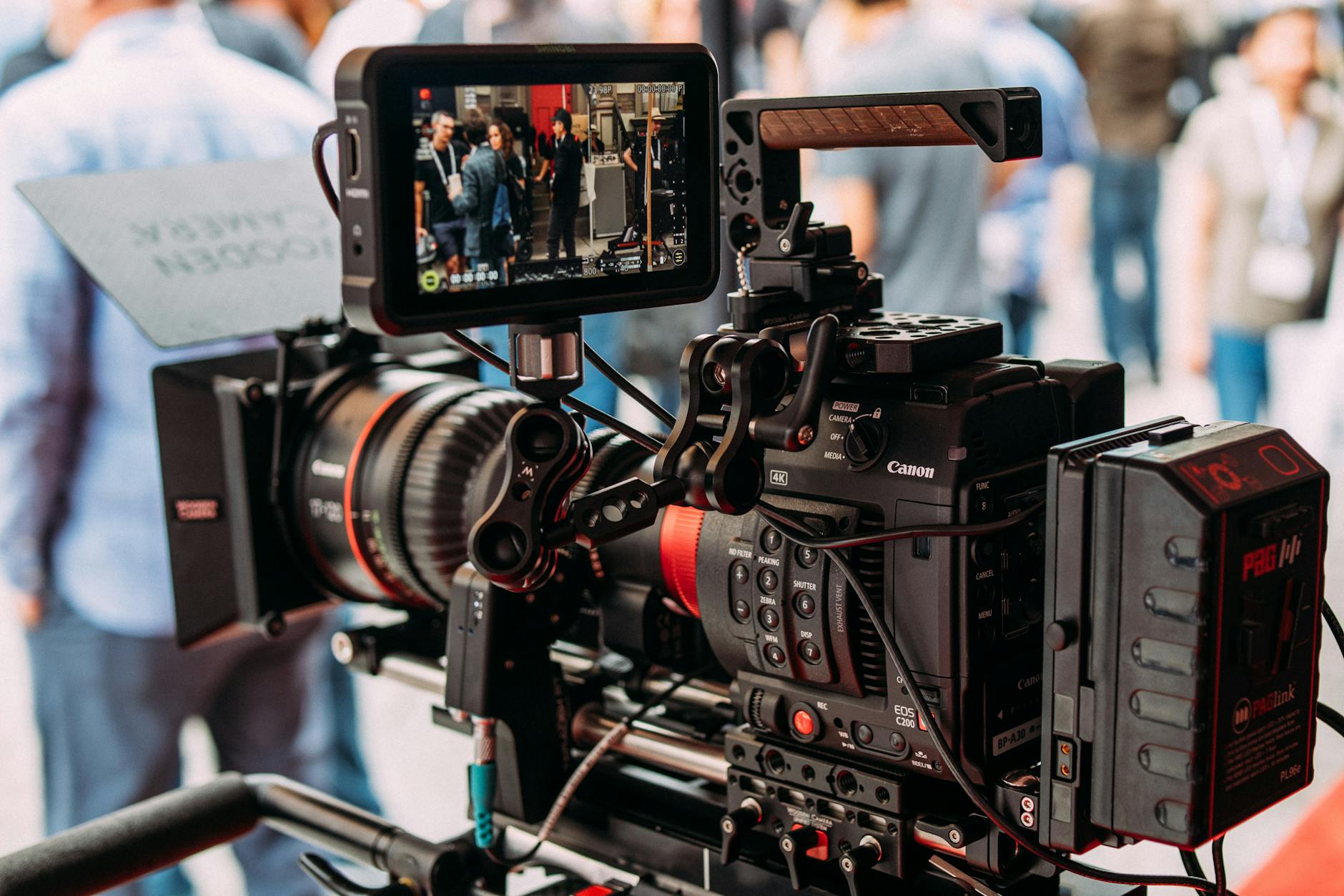 Close-up of a professional video camera setup capturing live footage during an outdoor event.
