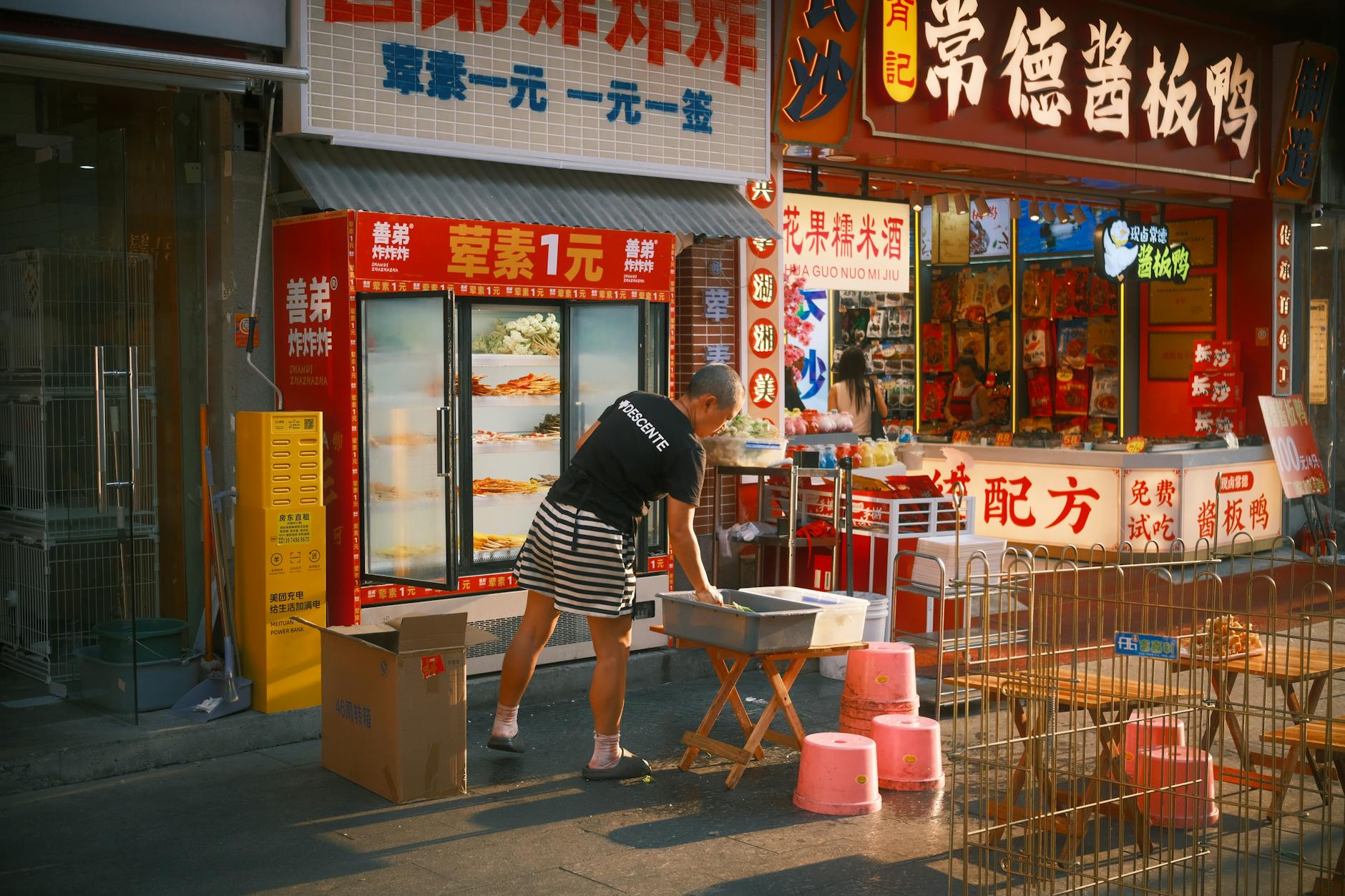 Street vendor preparing goods at a vibrant outdoor market with colorful signage.