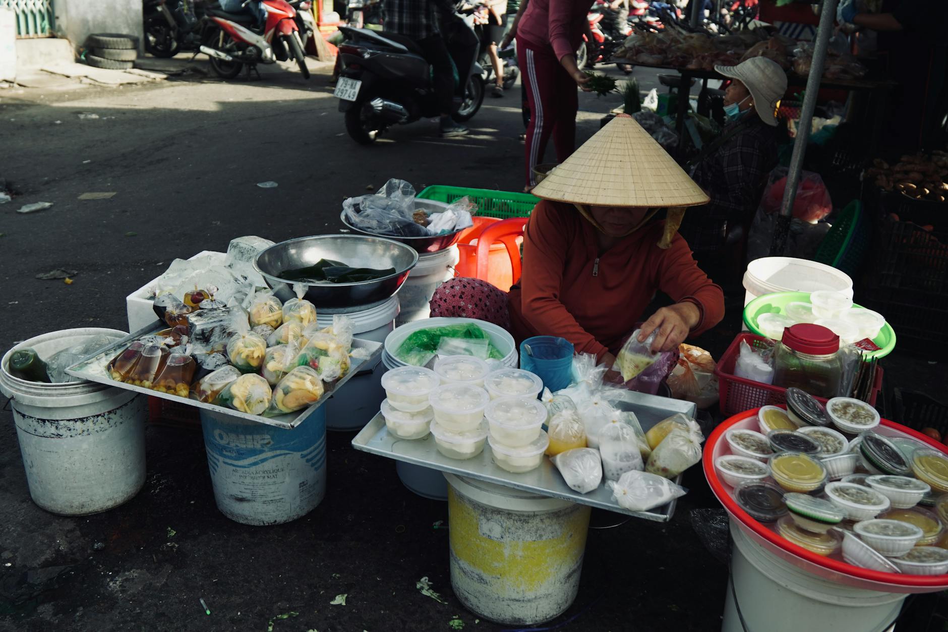 A vibrant street food market with an array of local dishes and a vendor wearing a conical hat.