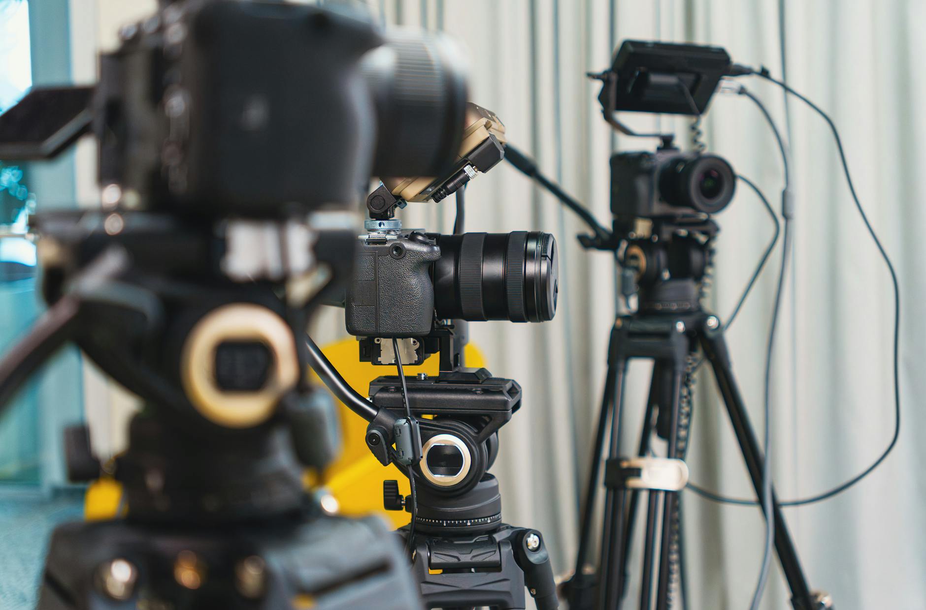 Close-up of high-end video cameras and tripods in a modern studio setting.
