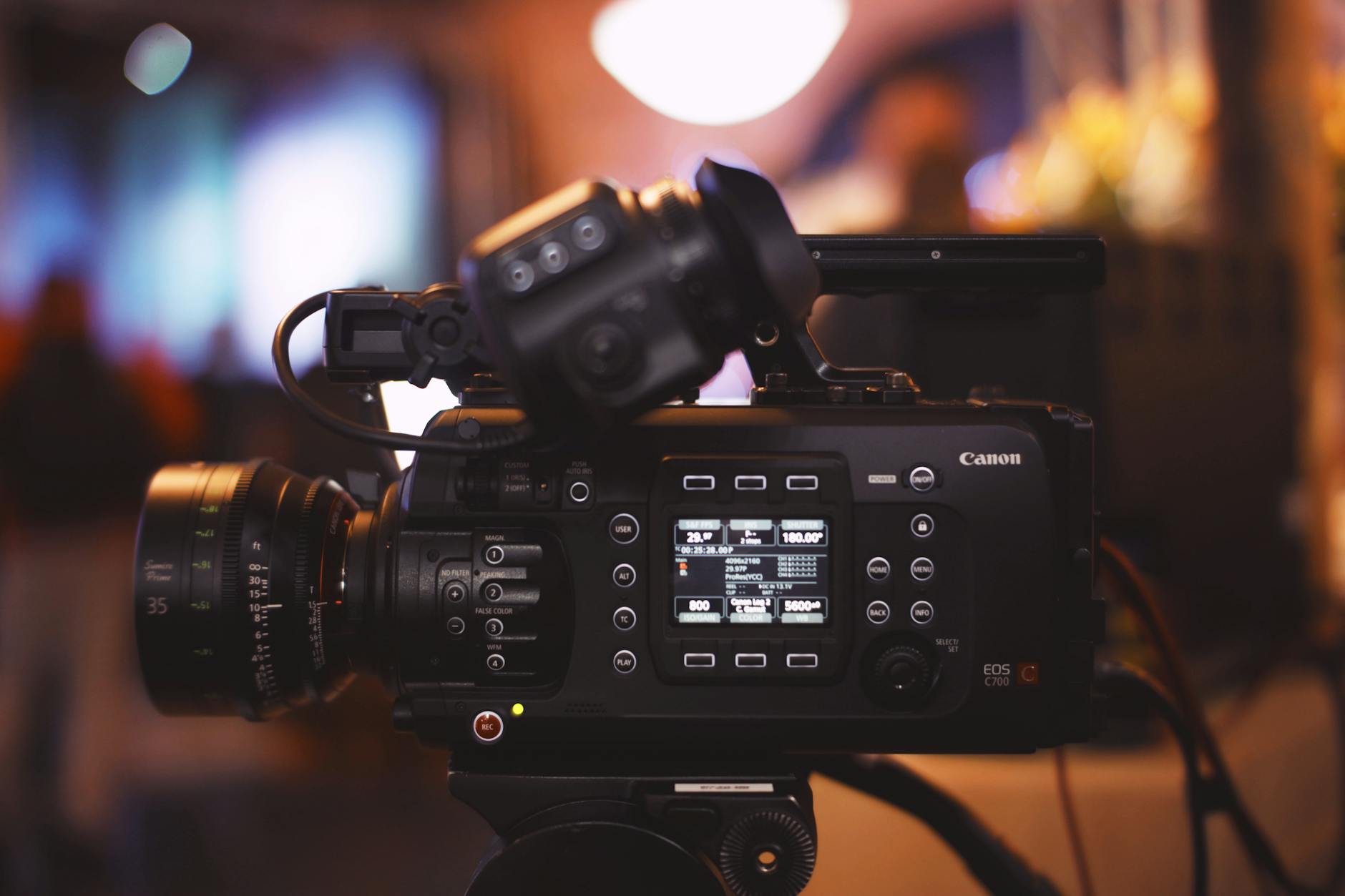 Close-up of a professional video camera in a studio environment, showcasing lens and controls.