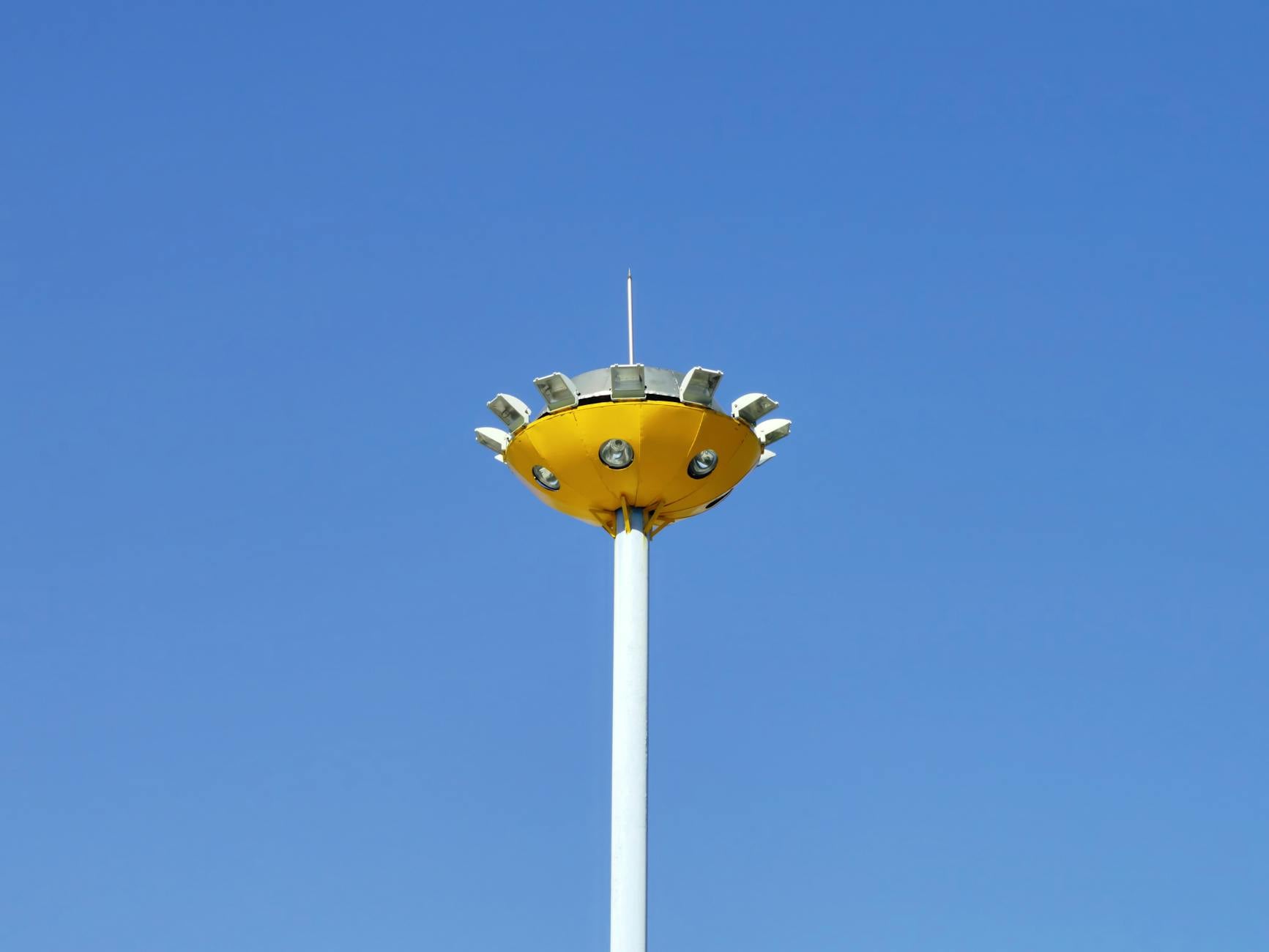 A yellow street lamp against a clear blue sky, offering a minimalistic and modern look.