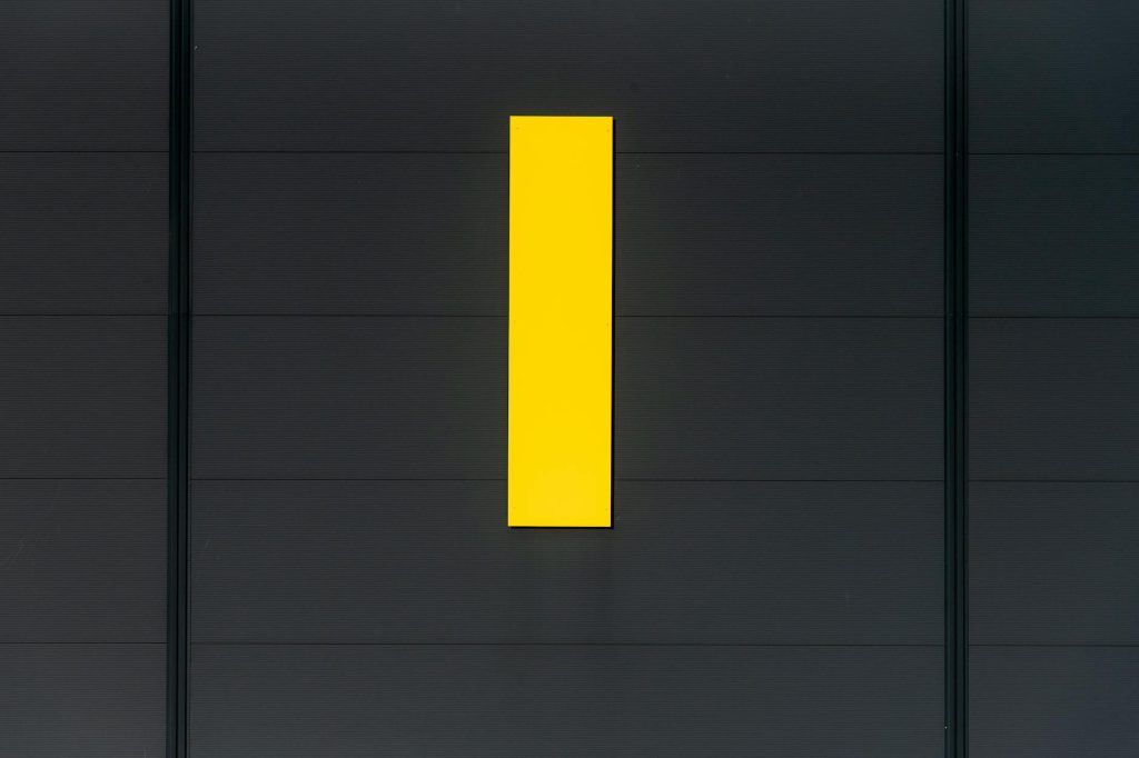 A minimalist composition showcasing a bright yellow rectangle against a dark wall, emphasizing contrast and simplicity.